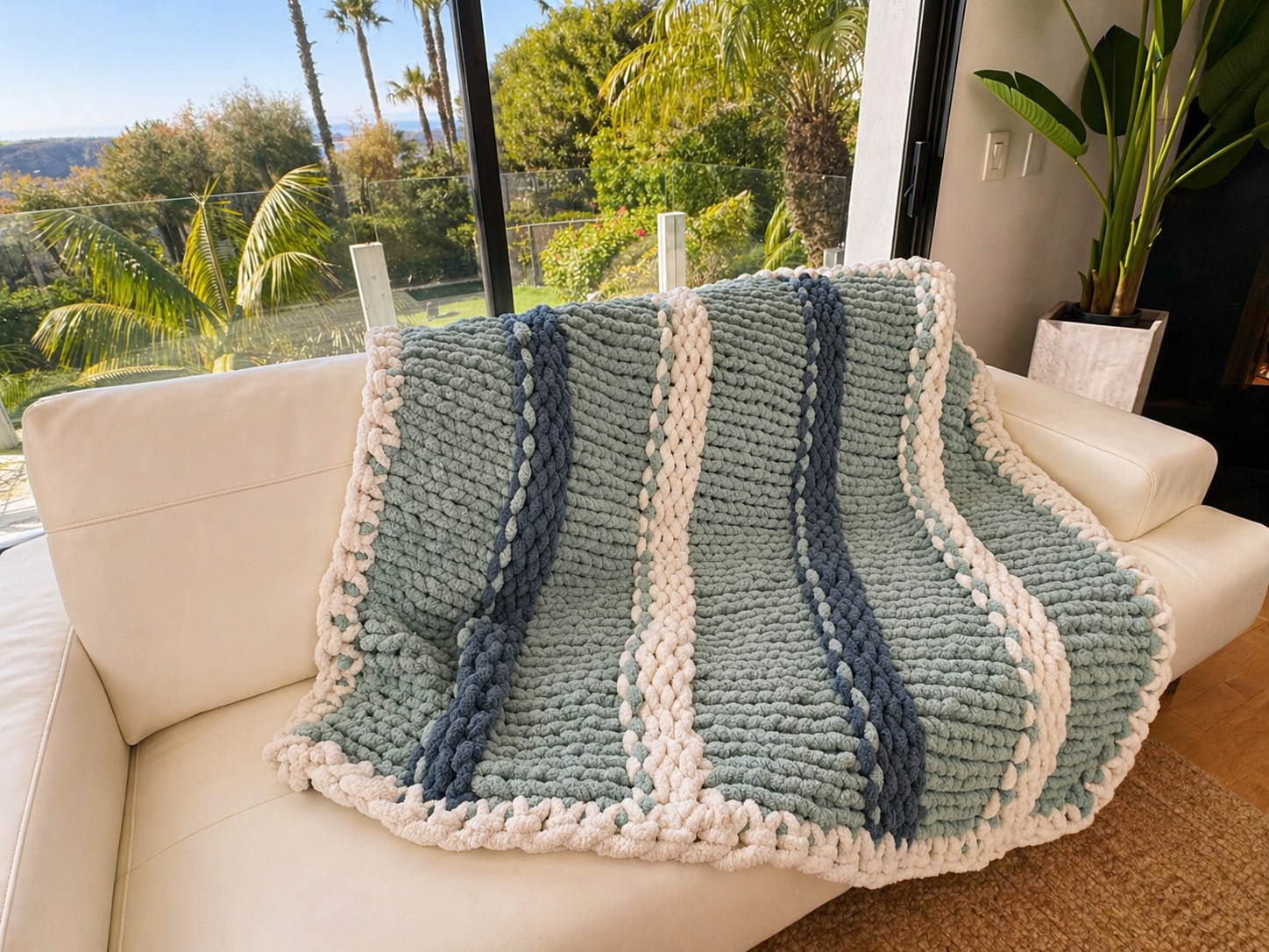 Teal and white striped chunky knit blanket on sofa